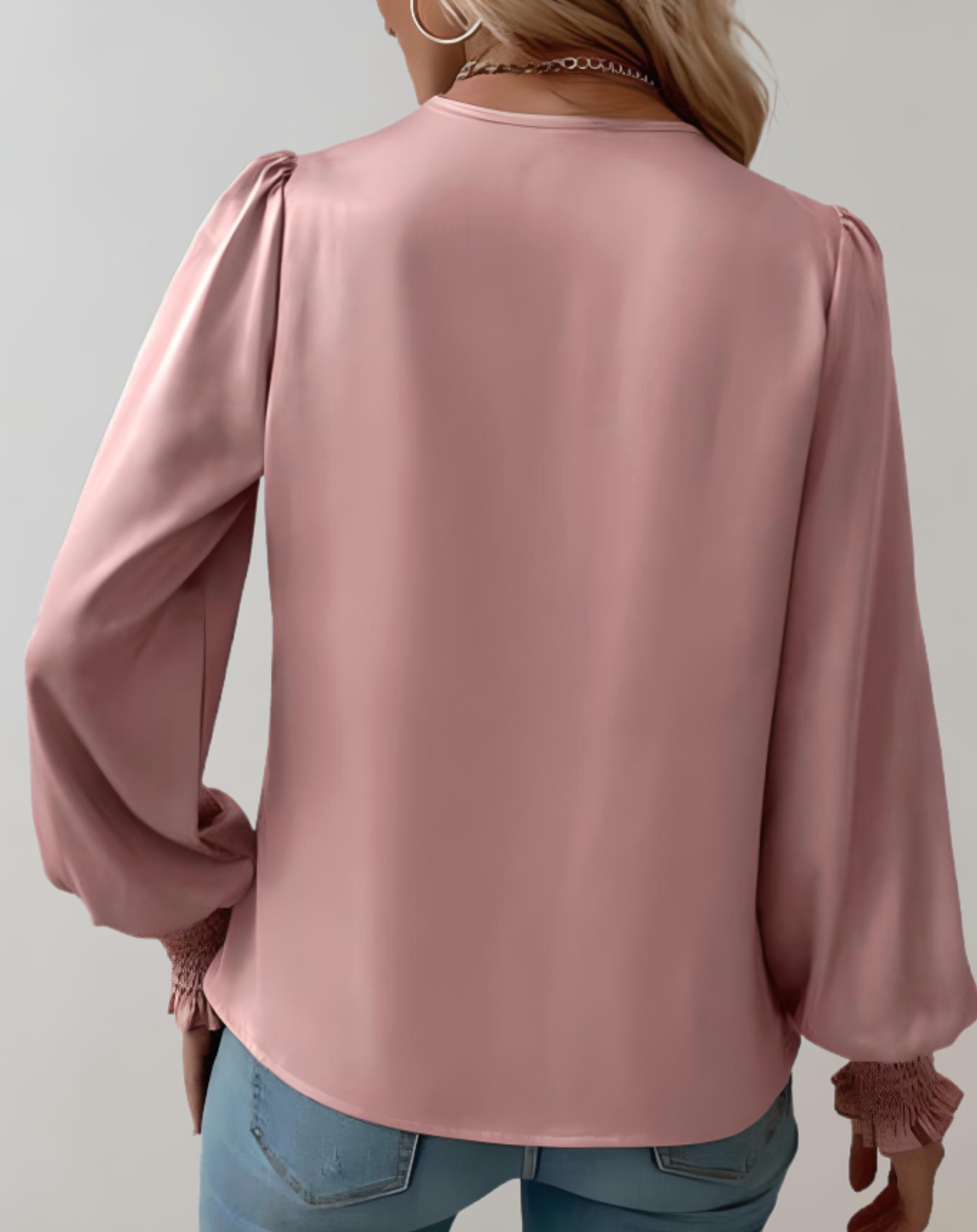Blusa rosa in raso da donna, maniche lunghe a sbuffo, polsini arricciati, abbinata a jeans. Elegante e moderna, ideale per moda casual.