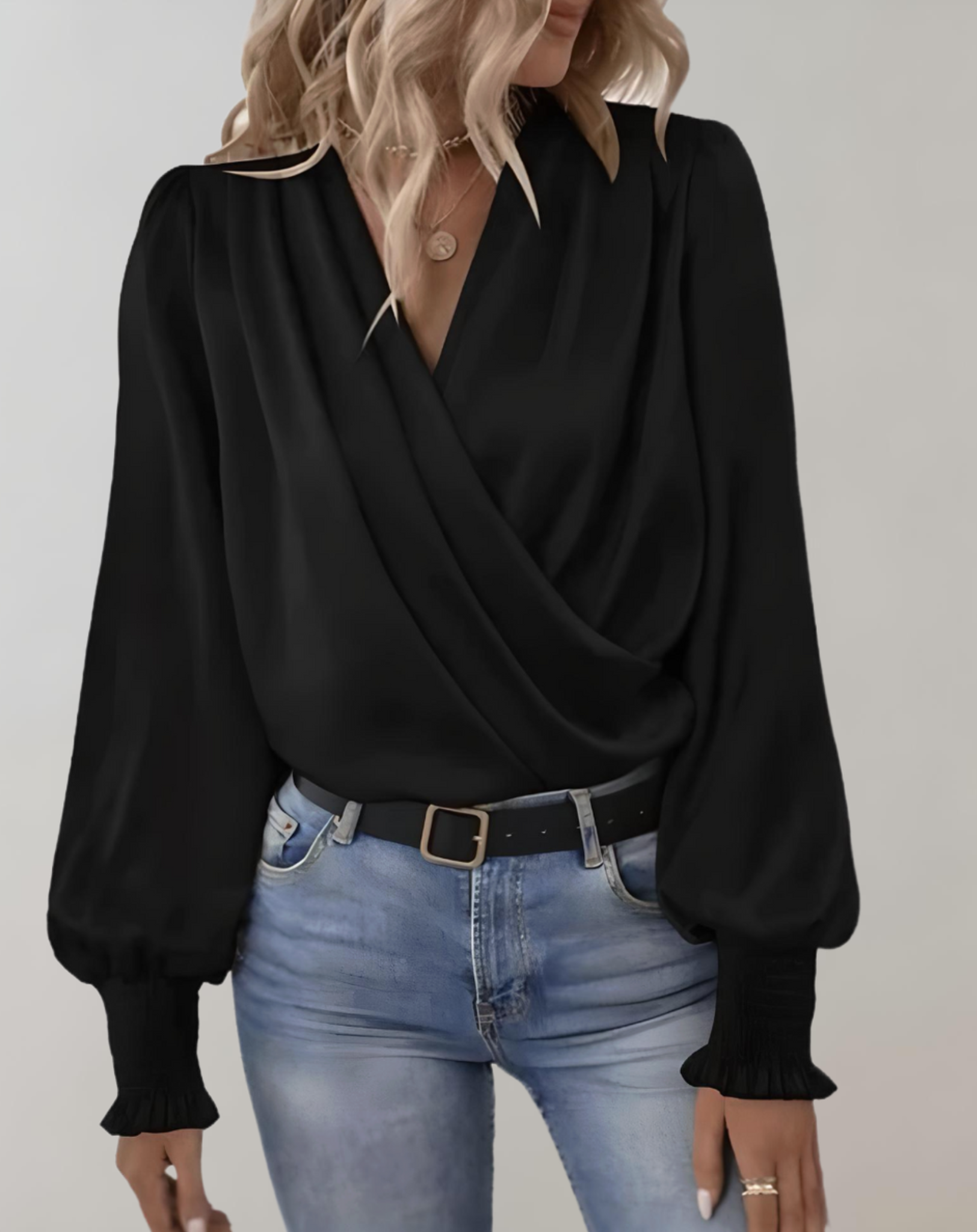 Blusa nera elegante con scollo a V incrociato, maniche lunghe a sbuffo, abbinata a jeans chiari. Moda donna, abbigliamento casual chic.