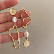Orecchini pendenti in oro con perle irregolari e moneta decorativa, design moderno e asimmetrico, gioielli eleganti per donna.