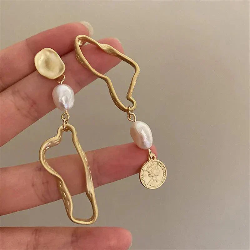 Orecchini pendenti asimmetrici in oro con perle d'acqua dolce e ciondolo moneta. Design moderno, gioielli eleganti per donna.
