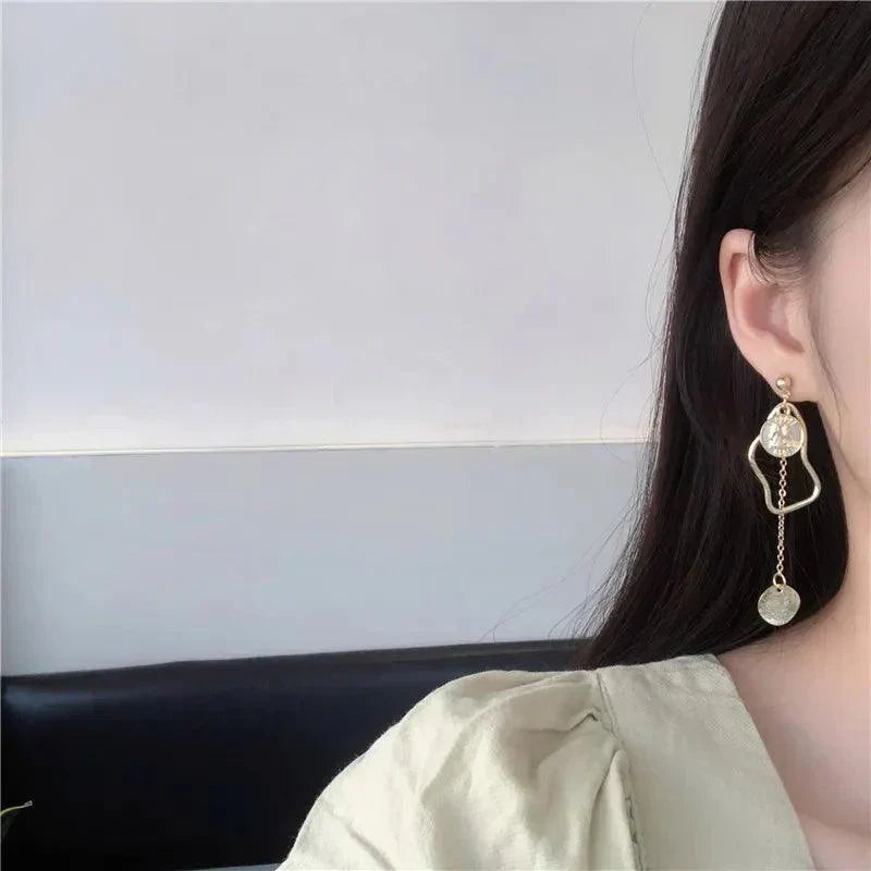 Orecchino pendente dorato su donna, design geometrico con cerchio e catena. Accessorio moda elegante, ideale per look sofisticati.