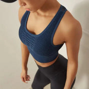 Donna in abbigliamento sportivo, indossa top blu a rete e leggings neri. Abbigliamento fitness, moda sportiva donna, outfit palestra.