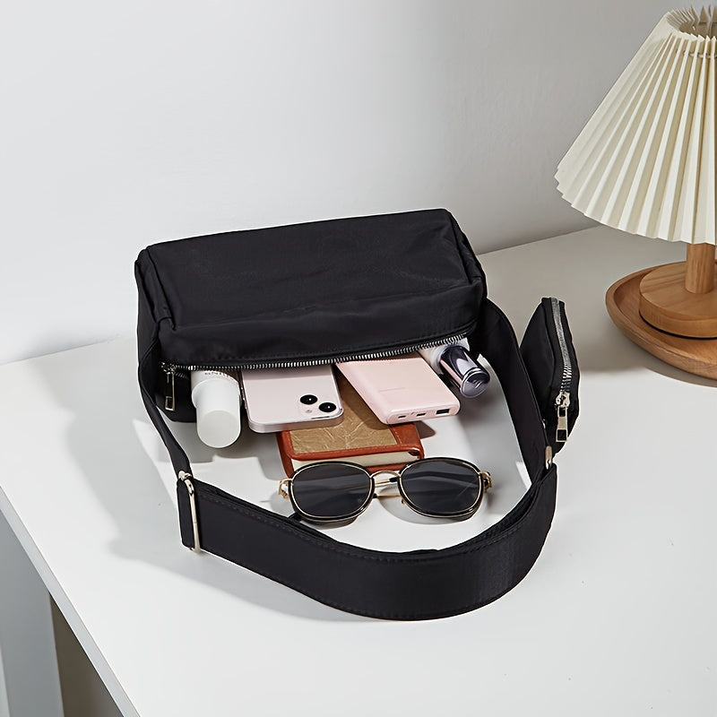 Borsa a tracolla nera su tavolo bianco con occhiali da sole, smartphone, rossetto e lampada. Accessori moda, eleganza, praticità quotidiana.