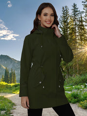 Donna sorridente con parka verde scuro, cappuccio e tasche, in un paesaggio montano al tramonto. Moda outdoor, giacca impermeabile elegante.