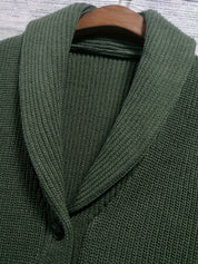 Cardigan verde in maglia a coste con colletto sciallato, chiusura a bottoni, su appendiabiti in legno. Maglione elegante e caldo per l'inverno.