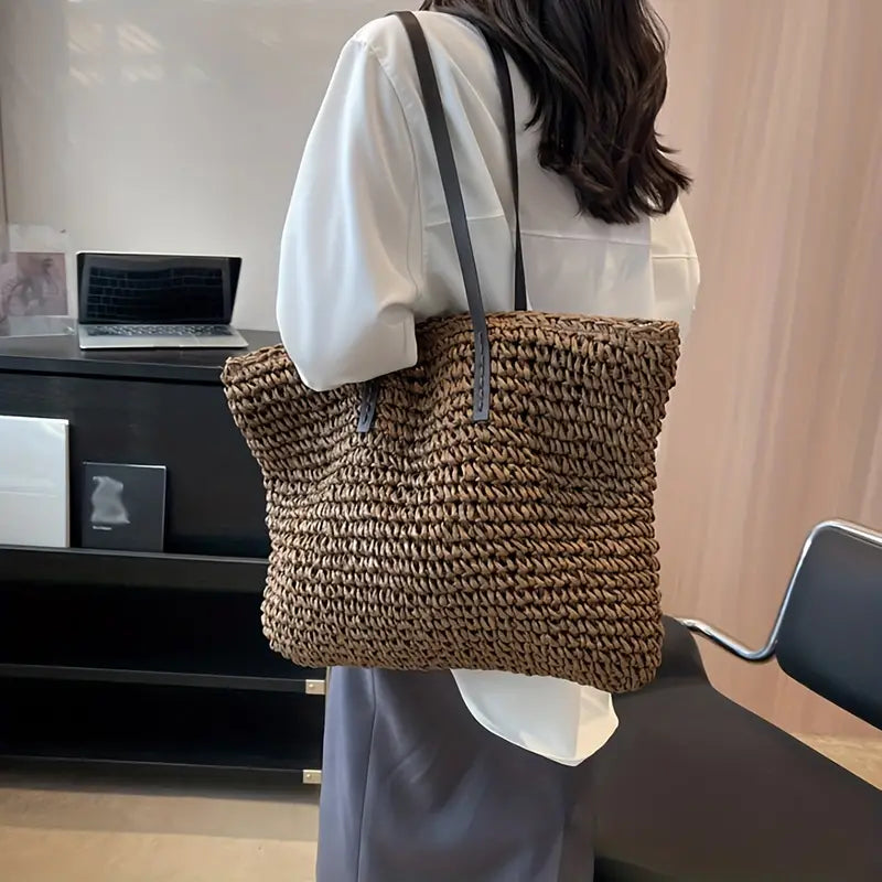 Donna con borsa a tracolla in paglia intrecciata, ufficio moderno, moda sostenibile, accessorio estivo, stile casual chic.