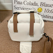 Zaino bianco in tessuto con spallacci marroni su sfondo di cartello. Design moderno, ideale per viaggi e uso quotidiano. Accessorio moda versatile.
