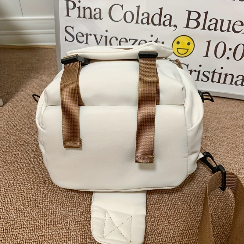 Zaino bianco in tessuto con spallacci marroni su sfondo di cartello. Design moderno, ideale per viaggi e uso quotidiano. Accessorio moda versatile.