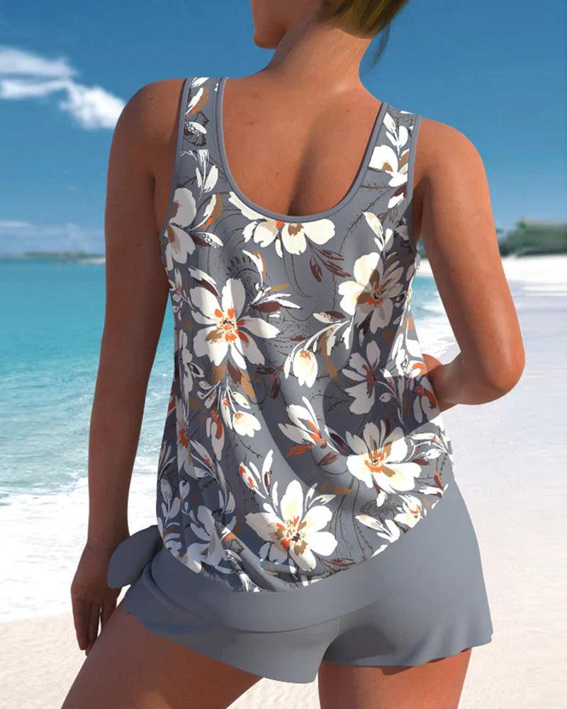 Donna in spiaggia con canotta floreale grigia e pantaloncini coordinati. Moda estiva, abbigliamento casual, look da vacanza al mare.