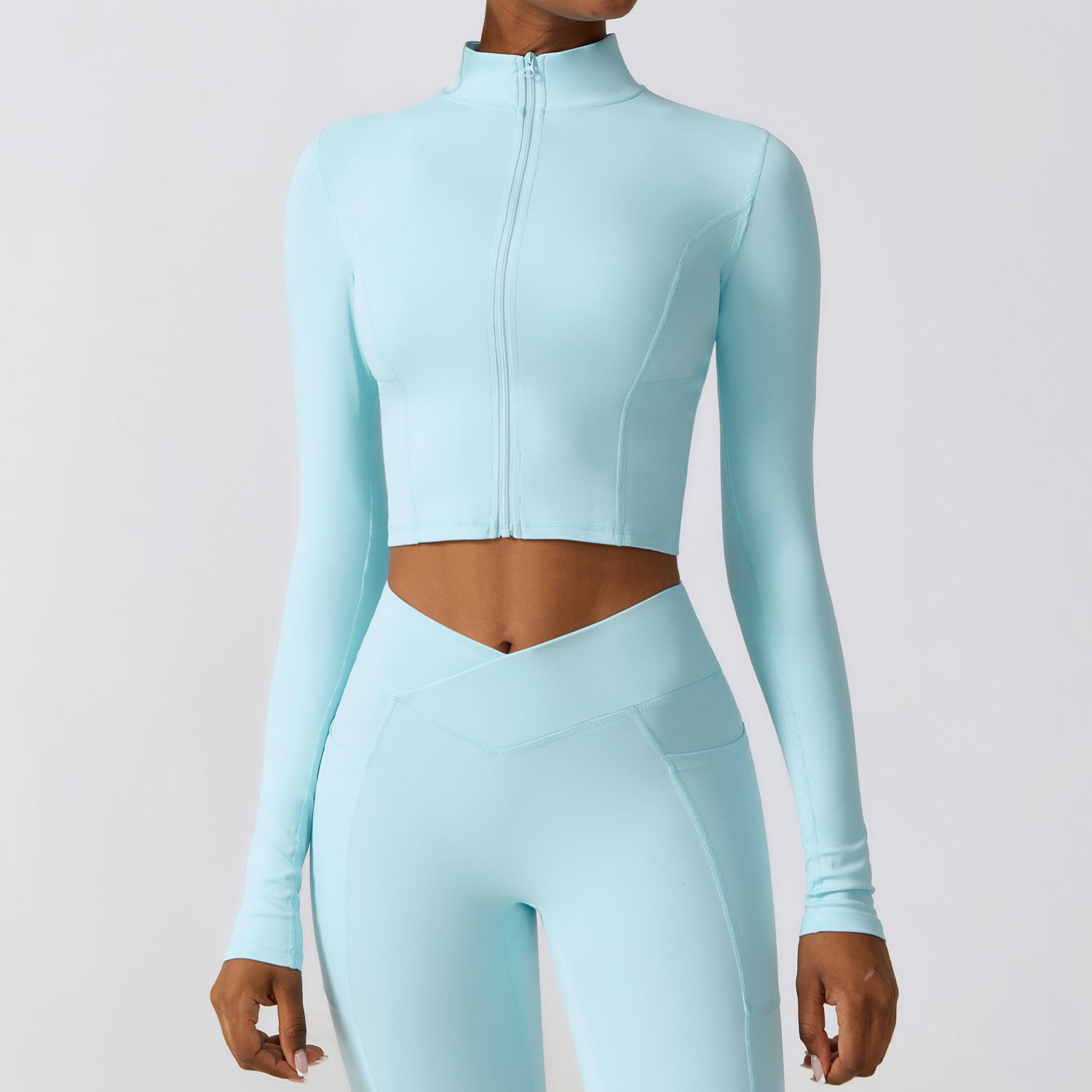 Donna in abbigliamento sportivo azzurro, top a maniche lunghe e leggings coordinati. Moda fitness, abbigliamento palestra, stile athleisure.
