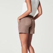 Donna in pantaloncini marroni, vista posteriore, con tasche, indossa una canotta bianca. Moda estiva casual, abbigliamento femminile trendy.