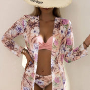 Cappello di paglia con scritta, costume da bagno rosa e copricostume floreale. Moda estiva donna, abbigliamento mare elegante e trendy.