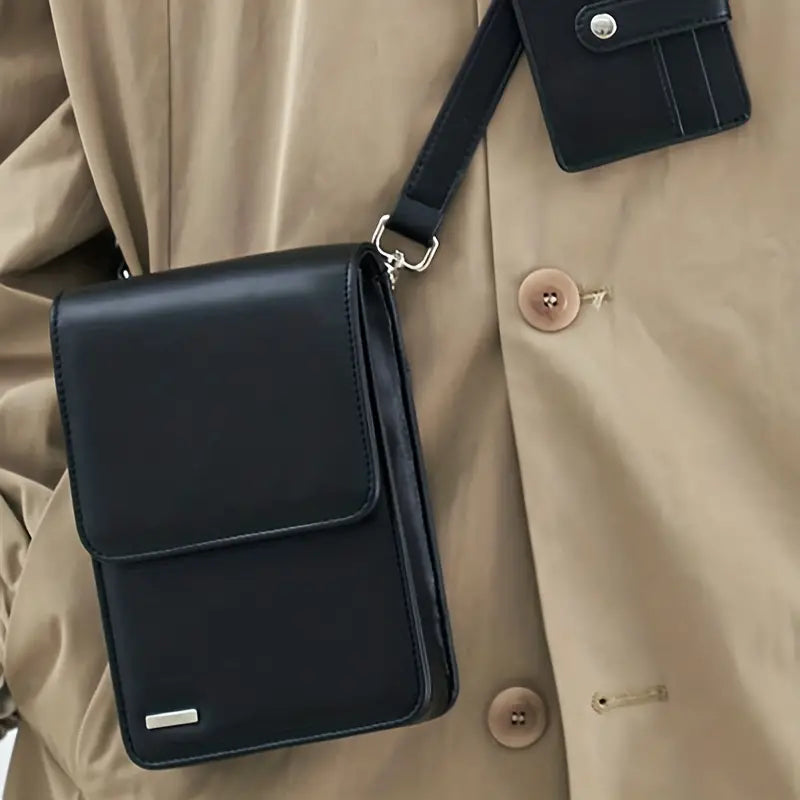 Borsa a tracolla nera in pelle, elegante e moderna, indossata su cappotto beige. Accessorio moda uomo, ideale per lavoro e tempo libero.