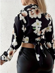 Blusa donna floreale nera a maniche lunghe, schiena scoperta, annodata, abbinata a pantaloni in ecopelle. Moda femminile elegante e trendy.