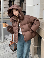 Donna con giacca invernale marrone, jeans larghi, borsa a tracolla e caffè da asporto. Moda urbana, abbigliamento casual, cappotto imbottito.