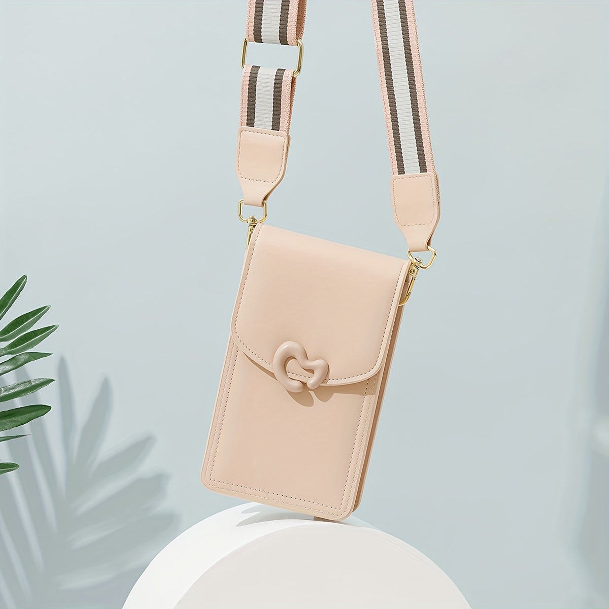 Borsa a tracolla beige in pelle sintetica con chiusura a cuore, cinturino regolabile a righe, design elegante e moderno, ideale per smartphone.