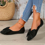 Scarpe ballerine nere con fiocco, indossate con jeans strappati. Moda donna, calzature eleganti, stile casual chic. Accessorio cavigliera colorata.