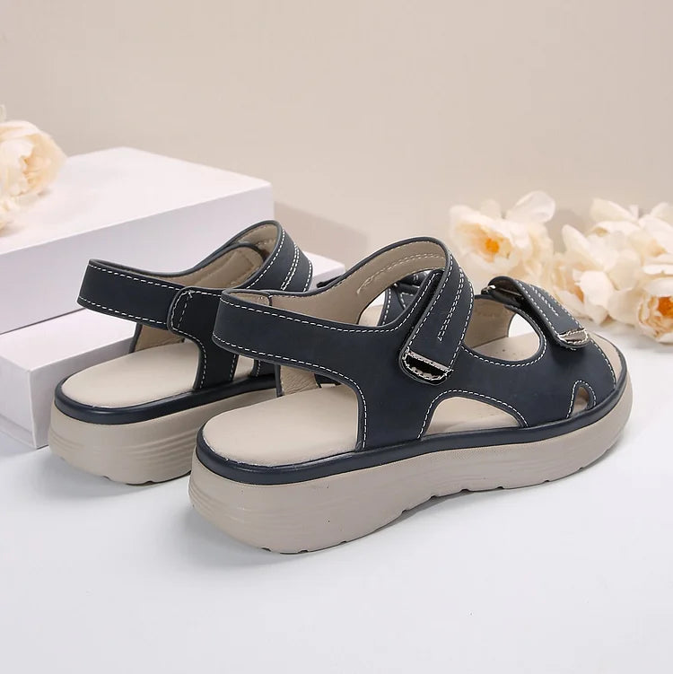 Sandali da donna in pelle nera con suola spessa beige, chiusura a strappo, design casual estivo, comodi e alla moda, su sfondo neutro.