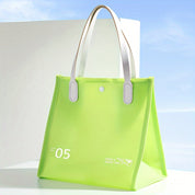 Borsa tote verde chiaro in PVC trasparente con manici bianchi, design moderno, ideale per shopping e viaggi. Accessorio moda estivo.
