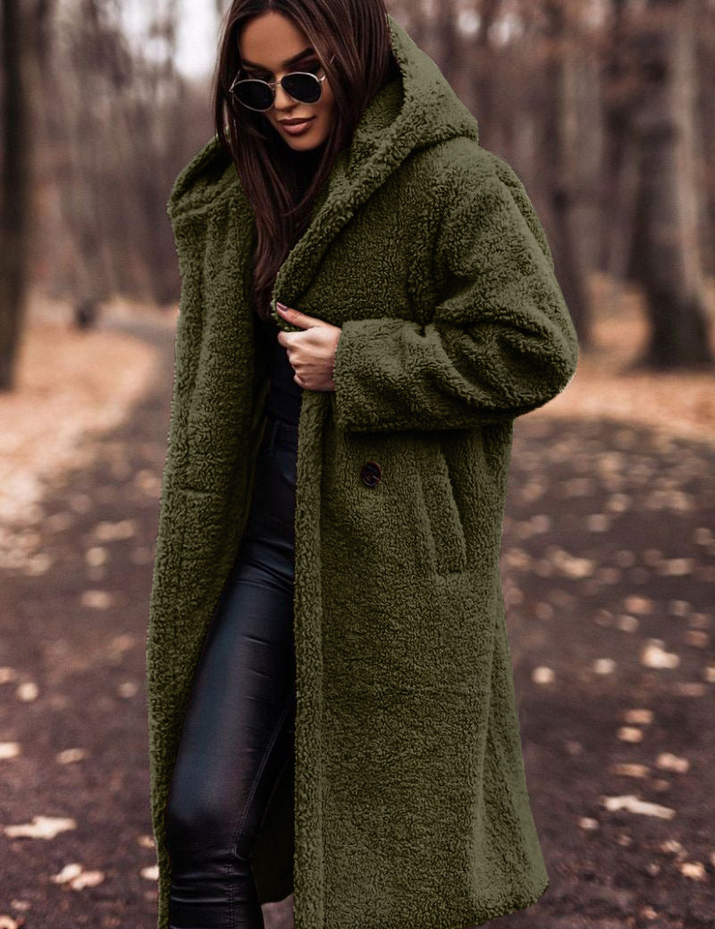 Donna con cappotto teddy verde oliva, occhiali da sole, pantaloni in pelle nera, in un parco autunnale. Moda autunno inverno, stile casual chic.