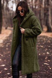 Donna con cappotto teddy verde oliva, occhiali da sole, pantaloni in pelle nera, in un parco autunnale. Moda autunno inverno, stile casual chic.