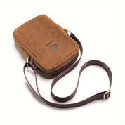 Borsa a tracolla in pelle marrone, design elegante e compatto, con cerniera e logo inciso. Accessorio moda uomo, ideale per uso quotidiano.
