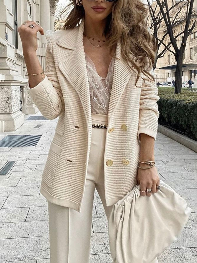 Donna con blazer bianco elegante, pantaloni coordinati, top in pizzo, borsa a mano e occhiali da sole. Moda femminile chic, abbigliamento primaverile.