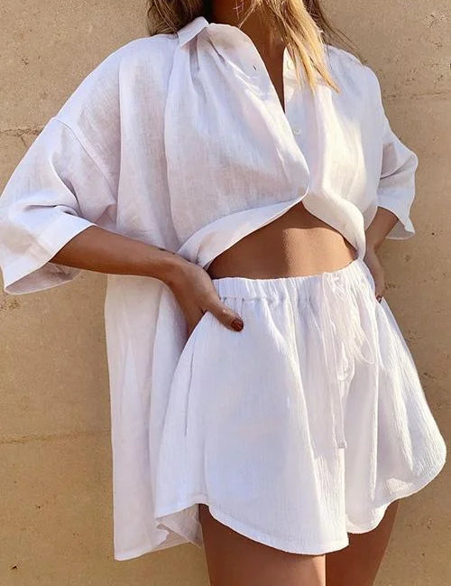 Donna con camicia bianca oversize e shorts coordinati in lino, moda estiva casual, abbigliamento leggero e traspirante, stile rilassato.