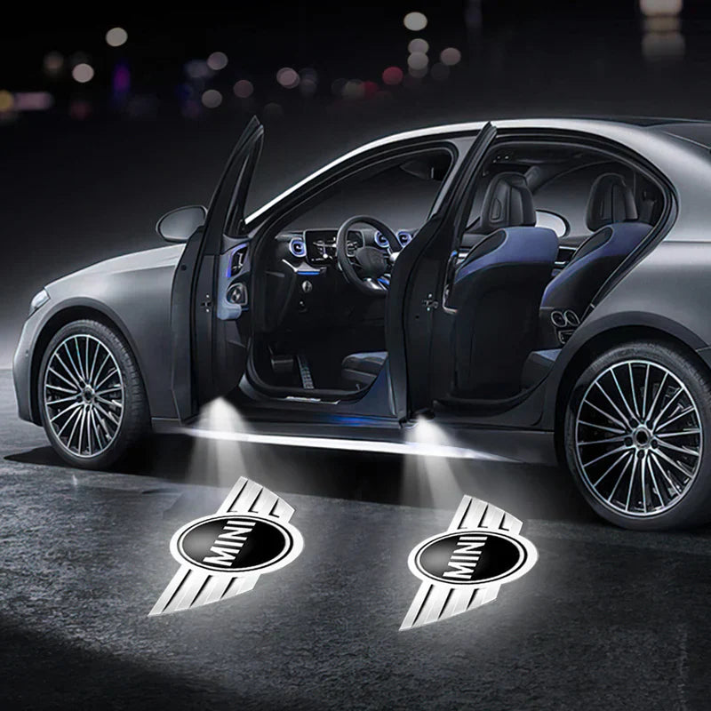 Auto grigia con portiere aperte, luci di cortesia proiettano logo MINI sul suolo. Design elegante, interni moderni, cerchi in lega.