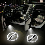Auto con portiere aperte e logo Nissan proiettato a terra, interni visibili. Illuminazione LED, design moderno. Accessori auto, personalizzazione.