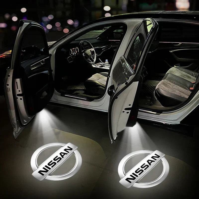 Auto con portiere aperte e logo Nissan proiettato a terra, interni visibili. Illuminazione LED, design moderno. Accessori auto, personalizzazione.
