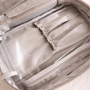 Borsa organizer da viaggio beige con tasche trasparenti e scomparti multipli, ideale per cosmetici e accessori. Design elegante e funzionale.