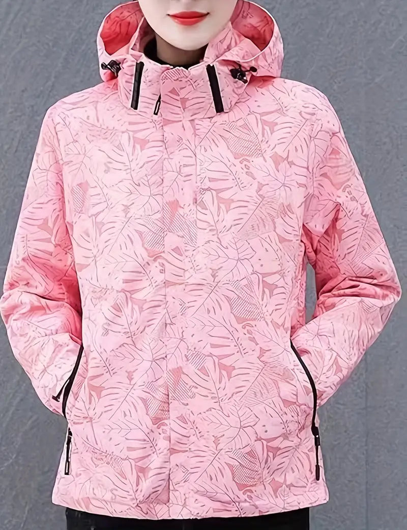 Giacca impermeabile donna rosa con cappuccio, motivo foglie tropicali, chiusura zip, tasche laterali. Abbigliamento outdoor moda autunno inverno.