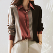 Camicia donna a maniche lunghe, design a righe verticali in seta multicolore, abbinata a pantaloni beige. Elegante moda femminile autunnale.