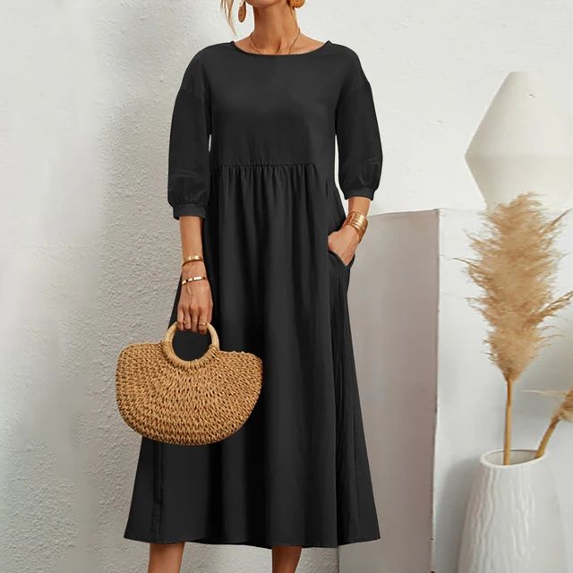 Abito nero lungo donna con maniche a tre quarti, borsa paglia intrecciata, sfondo minimalista bianco, decorazione pampas. Moda elegante casual.