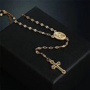 Collana rosario in oro con croce e medaglia su sfondo nero. Gioielli religiosi eleganti, accessori moda, regalo spirituale.