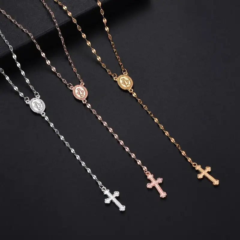 Quattro collane rosario in argento, oro, oro rosa e bronzo con croce pendente su sfondo nero. Gioielli religiosi eleganti e raffinati.