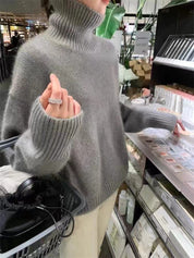 Donna con maglione grigio a collo alto, anello brillante, shopping in negozio di cosmetici. Maglione invernale moda, abbigliamento casual elegante.