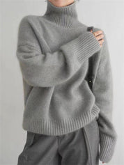 Maglione grigio a collo alto in lana, stile casual, indossato da una persona. Design morbido e caldo, ideale per l'inverno.