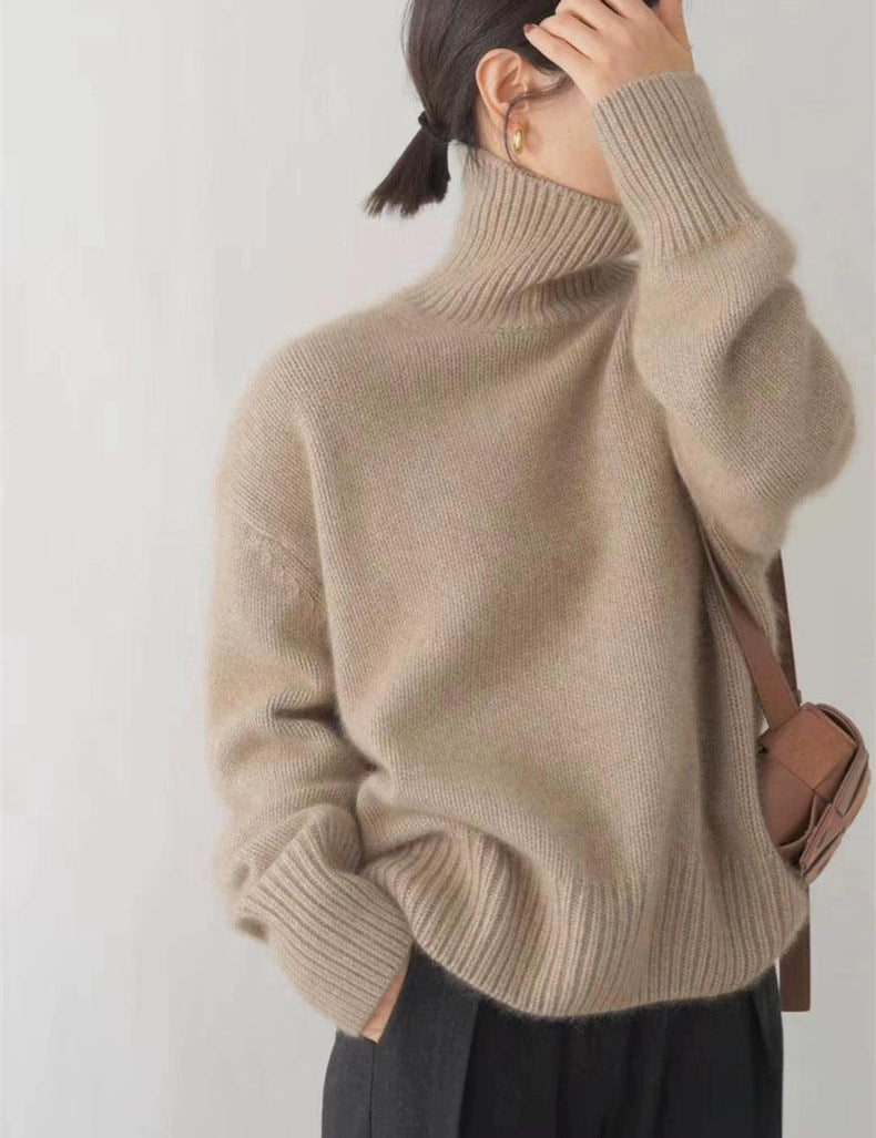 Donna con maglione beige a collo alto, borsa a tracolla marrone, orecchini dorati. Moda autunnale, abbigliamento casual elegante.