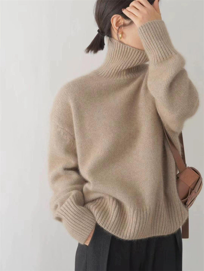 Donna con maglione beige a collo alto, borsa a tracolla marrone, orecchini dorati. Moda autunnale, abbigliamento casual elegante.