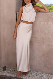 Abito lungo elegante color crema, senza maniche, con top drappeggiato e gonna fluida. Perfetto per eventi formali e cerimonie.