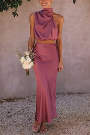 Abito da cerimonia elegante in raso rosa, top monospalla e gonna lunga, bouquet di fiori bianchi, moda donna, abbigliamento formale.