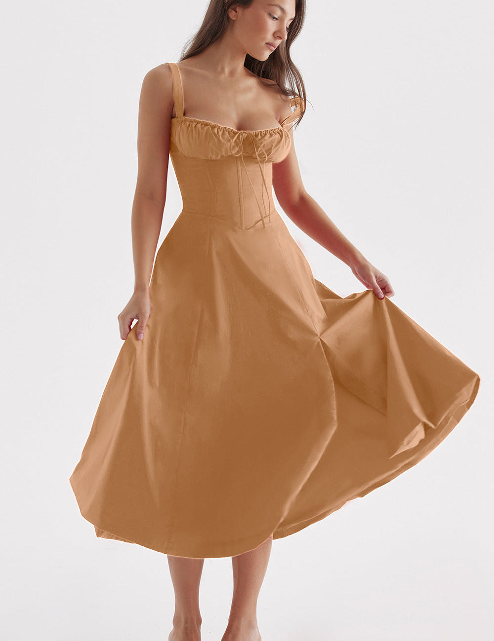 Donna in abito midi marrone chiaro, stile corsetto, con spalline sottili e gonna svasata. Moda elegante, abbigliamento femminile, tendenze 2023.