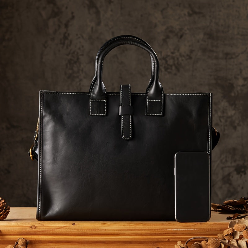 Borsa a mano in pelle nera elegante su sfondo scuro, con cuciture bianche a contrasto, accanto a uno smartphone per confronto dimensioni.