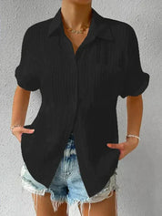 Camicia nera a maniche corte con colletto, abbinata a shorts di jeans chiari. Look casual estivo per donna, moda trendy e confortevole.