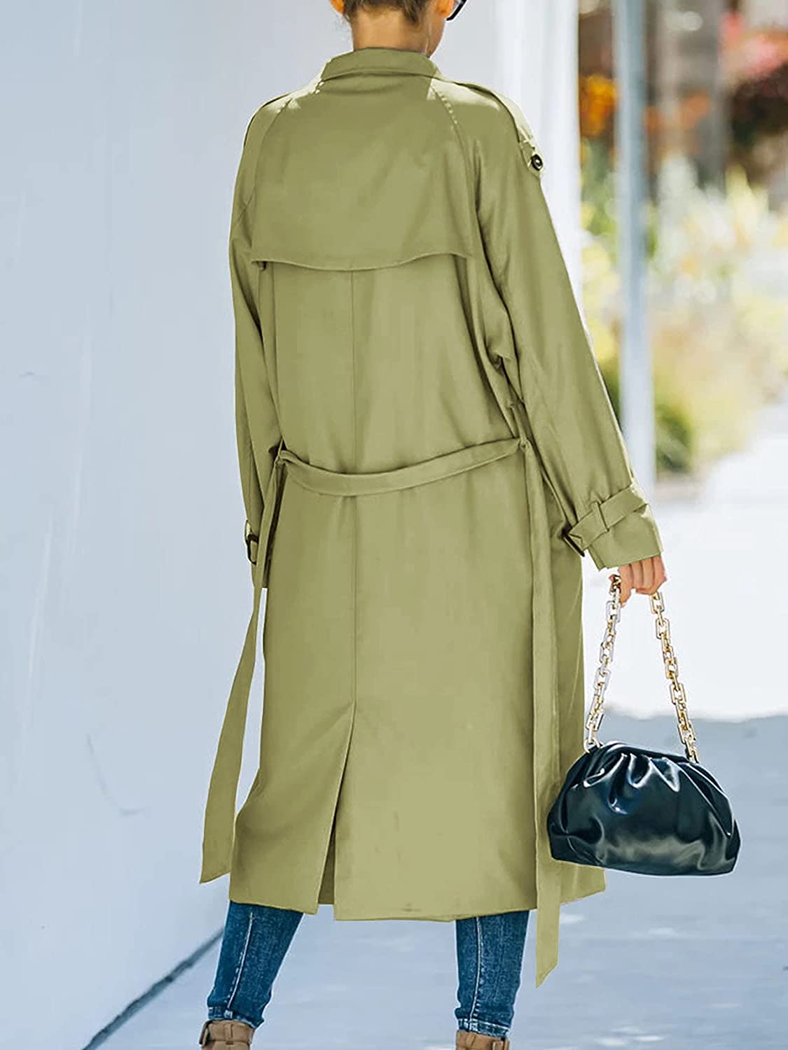 Cappotto trench verde oliva donna, lungo, con cintura, indossato all'aperto. Borsa nera a catena dorata. Moda autunnale casual.