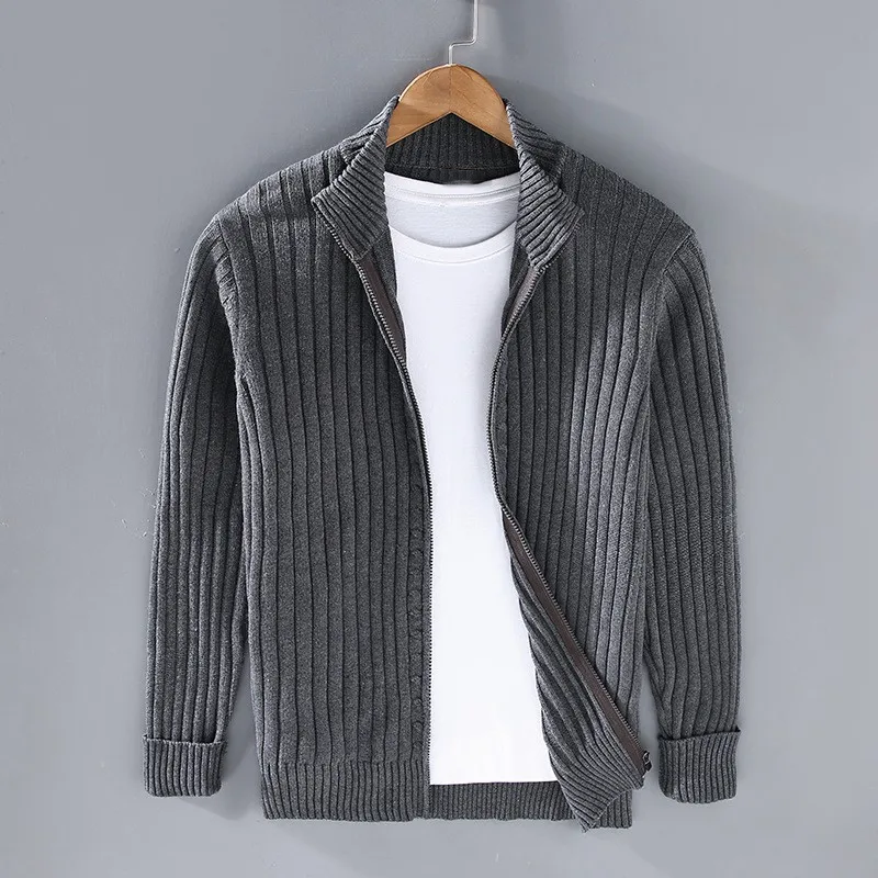 Cardigan grigio a coste in lana, aperto su maglietta bianca, appeso su gruccia di legno. Moda uomo, abbigliamento casual elegante.