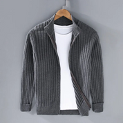 Cardigan grigio a coste in lana, aperto su maglietta bianca, appeso su gruccia di legno. Moda uomo, abbigliamento casual elegante.