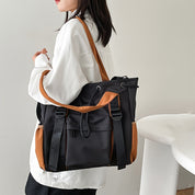 Zaino moda donna nero e marrone, design elegante, tasche multiple, indossato su giacca bianca. Accessorio versatile per scuola o lavoro.